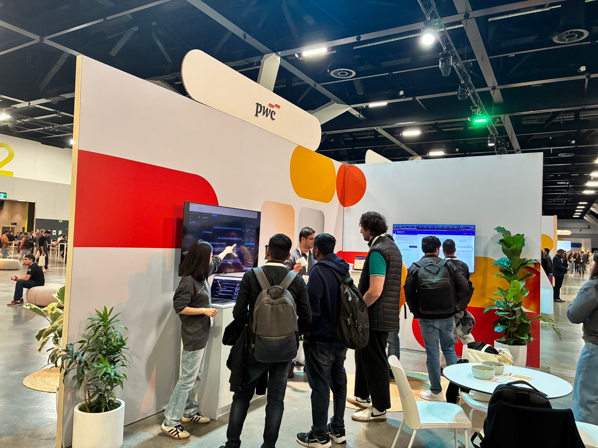 Ming demonstrating an enterprise AI system in a PwC booth setting.